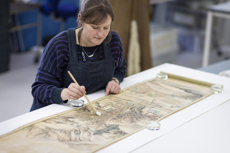 Image of woman working on a piece of art with a paintbrush