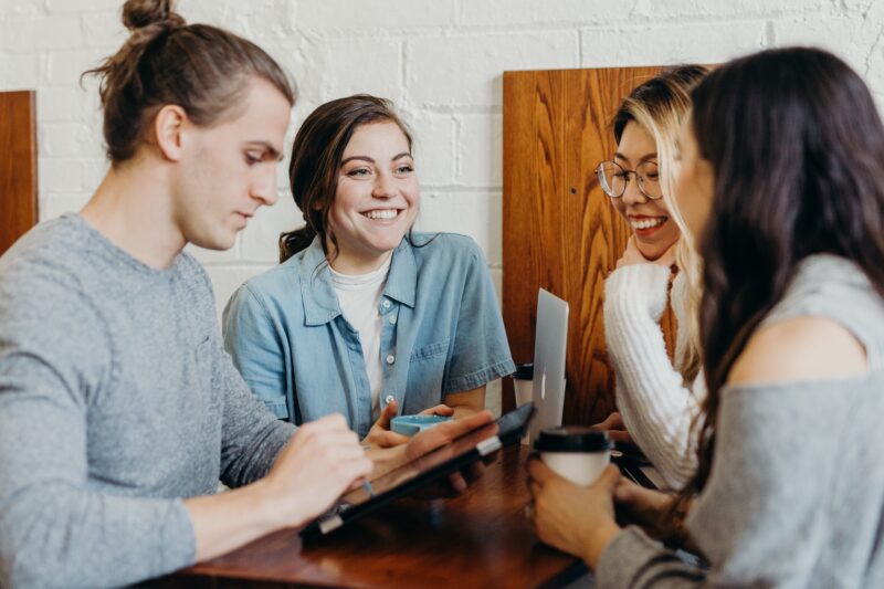 Four people sitting around a table, working and laughing